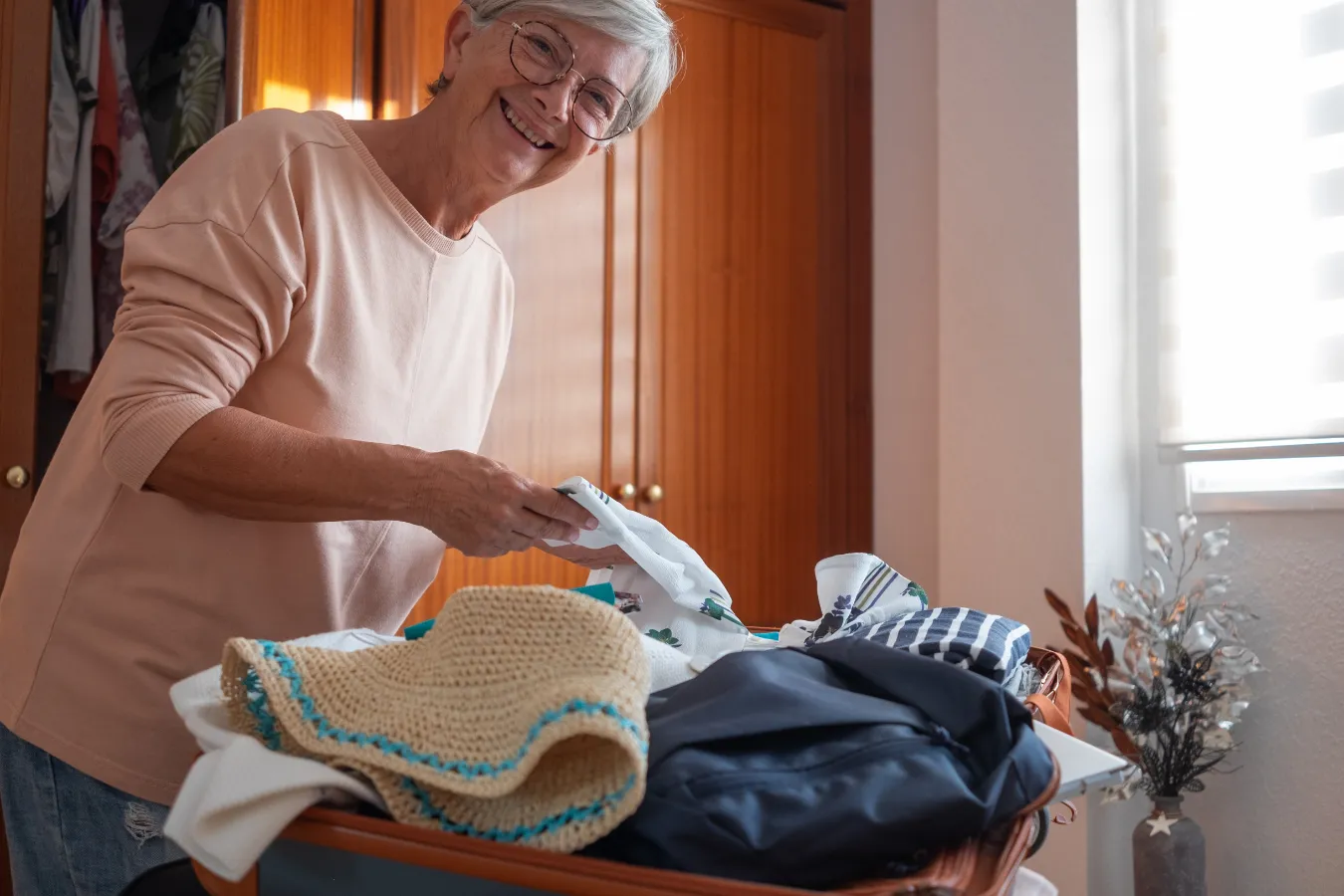 seniorka pakująca rzeczy do walizki